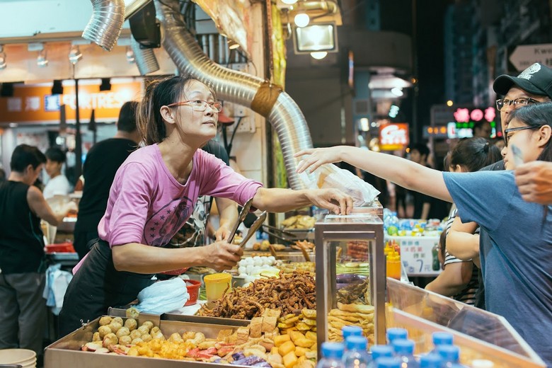 Khách du lịch trả tiền mặt sau khi mặc cả thành công tại một quầy hàng