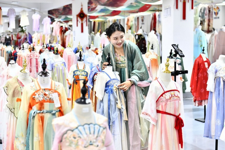Nhân viên tiệm hỗ trợ khách kiểm tra trang phục trước khi thuê