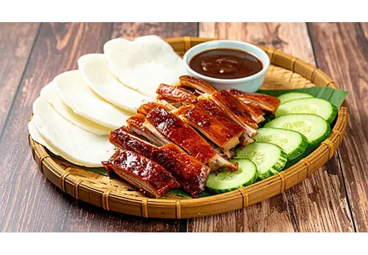Đĩa vịt quay nguyên con kèm bánh tráng, hành lá, dưa chuột và sốt tương ngọt