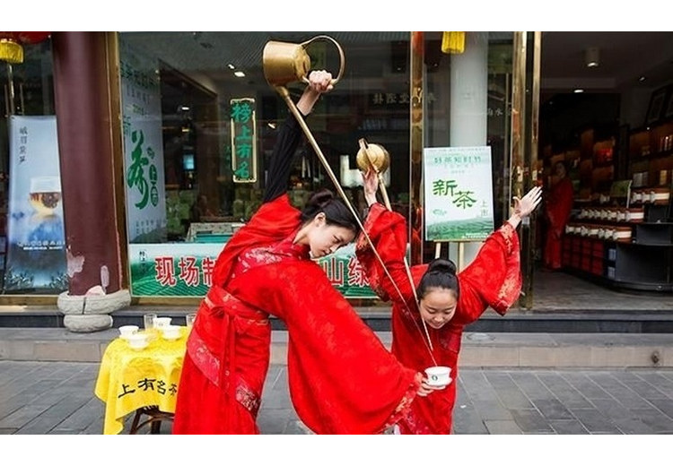 Nghệ nhân rót trà bằng ấm vòi dài giữa hàng ghế tre ở Hạc Minh Trà Xã