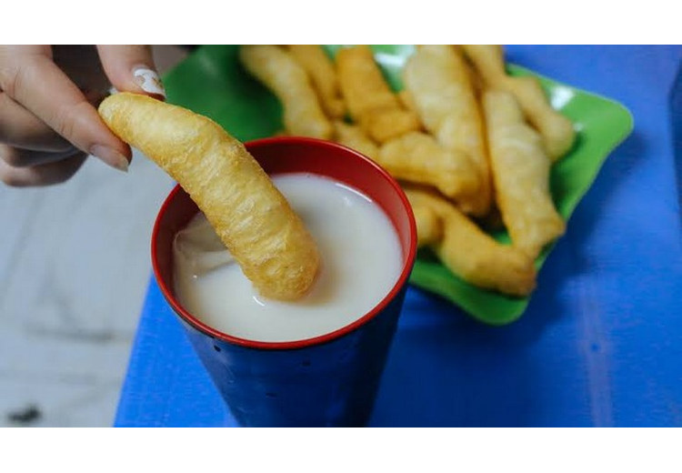 Quẩy chiên vàng giòn bẻ khúc chấm vào cốc sữa đậu nành nóng